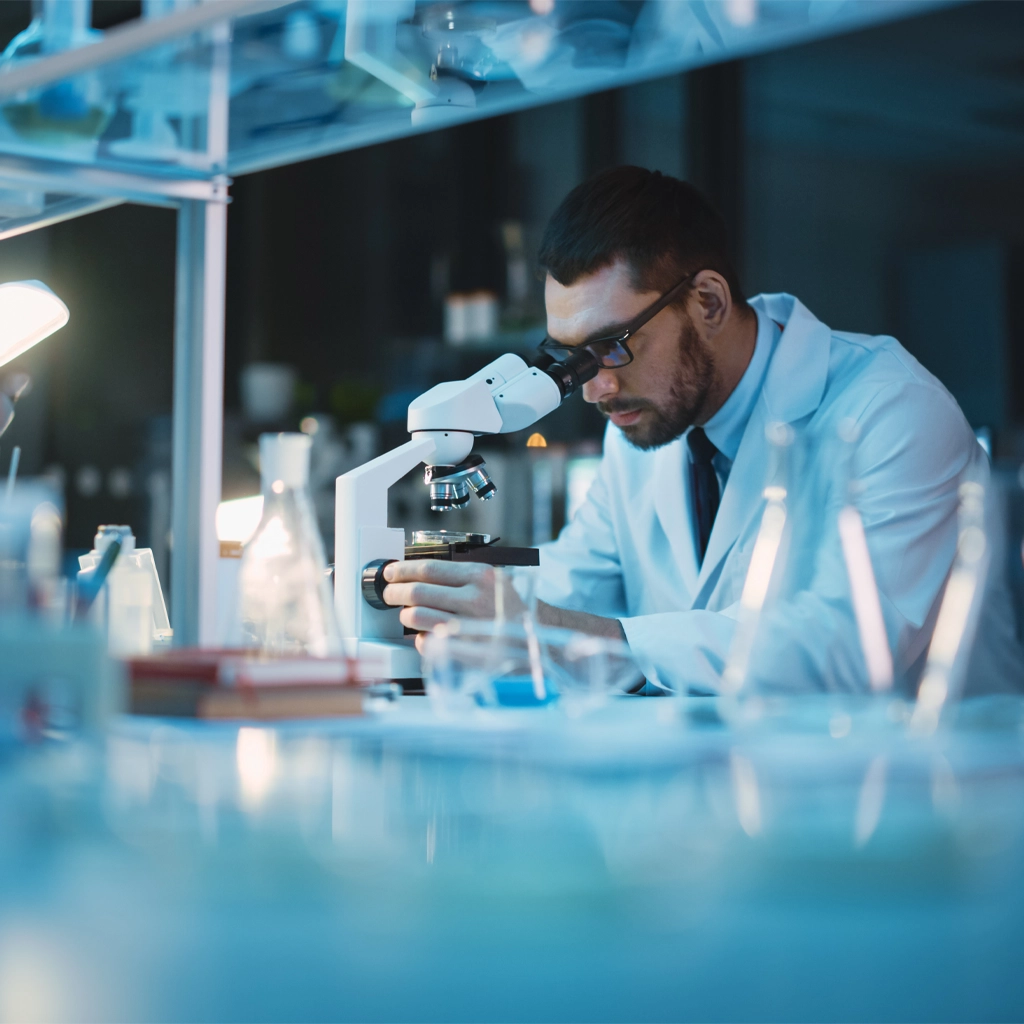 Man in a laboratory looking thru a microscope